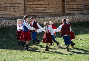 Dzieci w ludowych strojach, tańczące na świeżym powietrzu